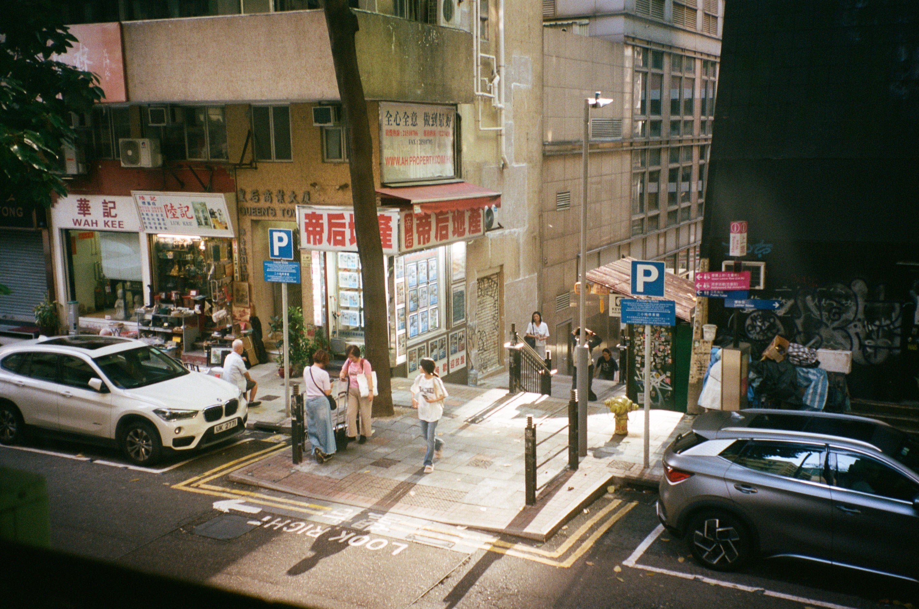 People waiting to cross at a street corner in Sheung Wan, Hong Kong, film photography by Loud Etudes
